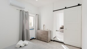 Une chambre d’hôtel moderne équipée d’un lit, d’une commode, d’une porte coulissante et d’un appareil de climatisation.