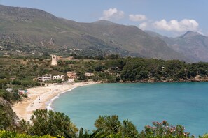 A coastal landscape with a beach, buildings, and mountains.