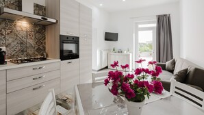 Une cuisine moderne équipée d’une cuisinière, d’un four et d’un crédence décorée. On y trouve un coin repas avec une table et des chaises, ainsi qu’un canapé dans le salon.