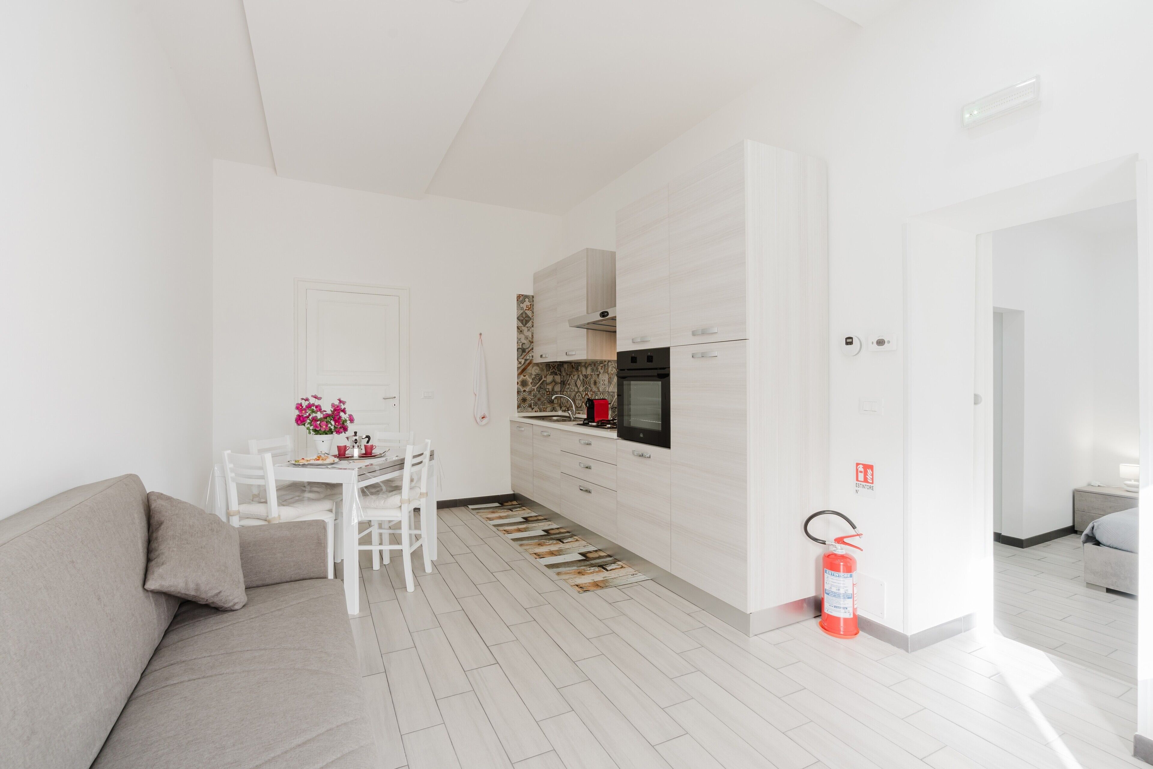 Una cocina moderna con armarios blancos, una mesa de comedor con sillas y un sofá.