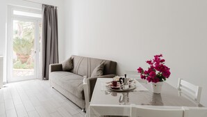 Un salon moderne avec un canapé, une table à manger et une cafetière, ainsi qu’une plante en pot.