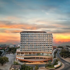 A modern hotel with a curved facade, multiple floors, and a rooftop terrace. - Amari Vientiane Laos (Vientiane)