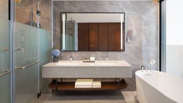 A modern bathroom with a large mirror, two sinks, a bathtub, and a glass-enclosed shower.