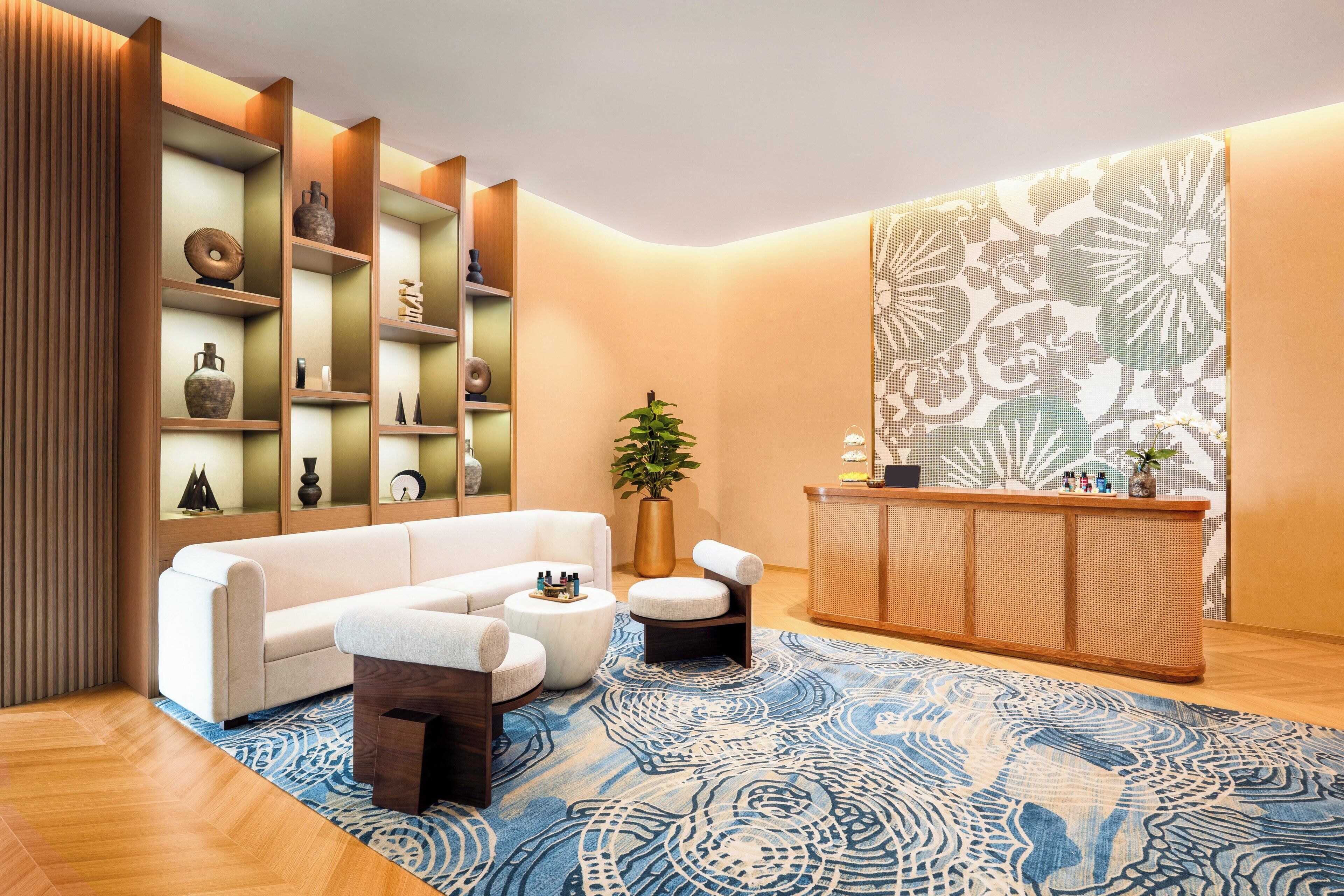 A modern living room with a white sofa, a round coffee table, and a wooden reception desk.