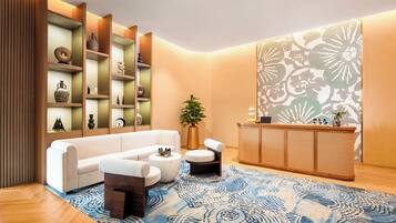 A modern living room with a white sofa, a round coffee table, and a wooden reception desk.