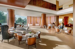 A spacious lobby with modern furniture, large pillars, and a high ceiling.