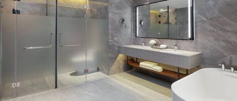 Un baño moderno con ducha envuelta en vidrio, una bañera independiente grande y un tocador con espejo.