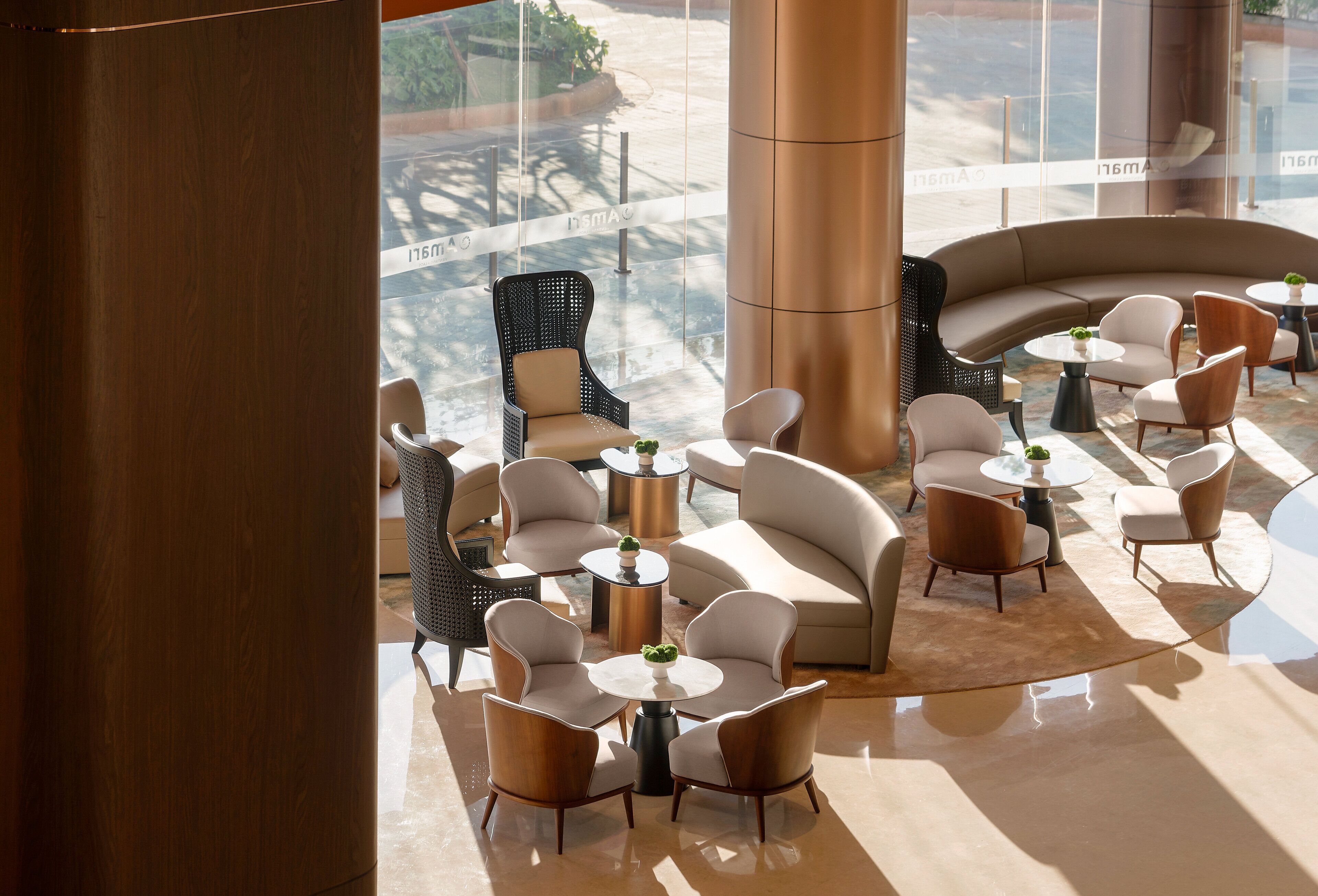 Een moderne zithoek met een gebogen bank, ronde tafels en verschillende stoelen.