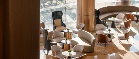 A modern lounge area with a curved sofa, round tables, and various chairs.