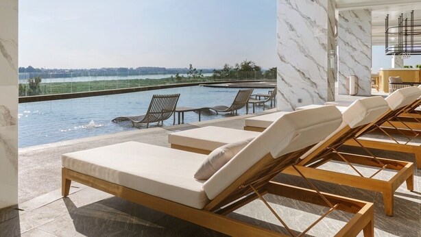 A modern indoor pool area with lounge chairs and a view of a body of water. - Amari Vientiane Laos (Vientiane)
