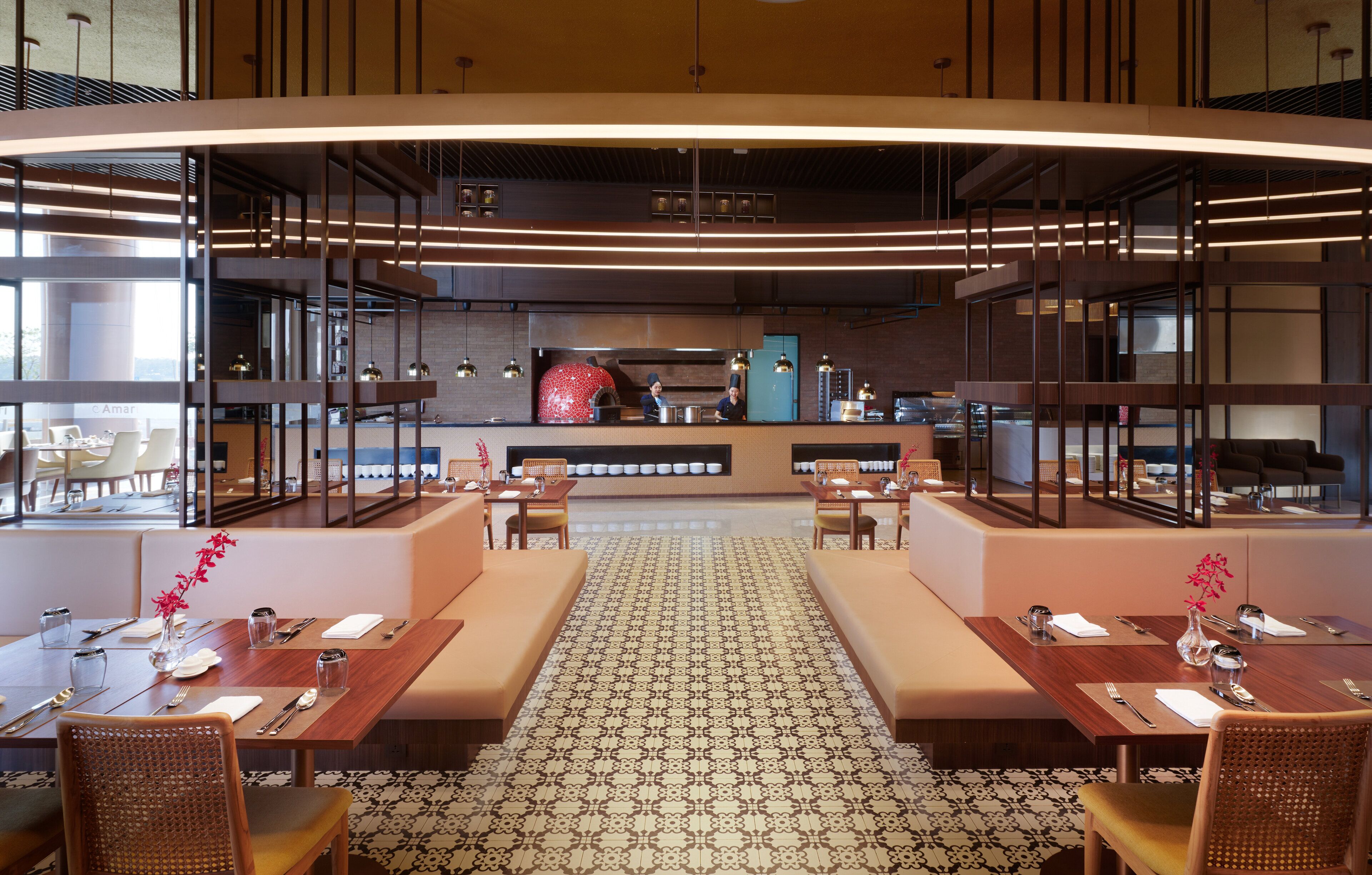 En moderne restaurant med centralt køkken, høje lofter og et mønstret gulv.