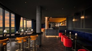 A modern bar area with high stools, a bar counter, and a seating area with red chairs. - Amari Vientiane Laos (Vientiane)