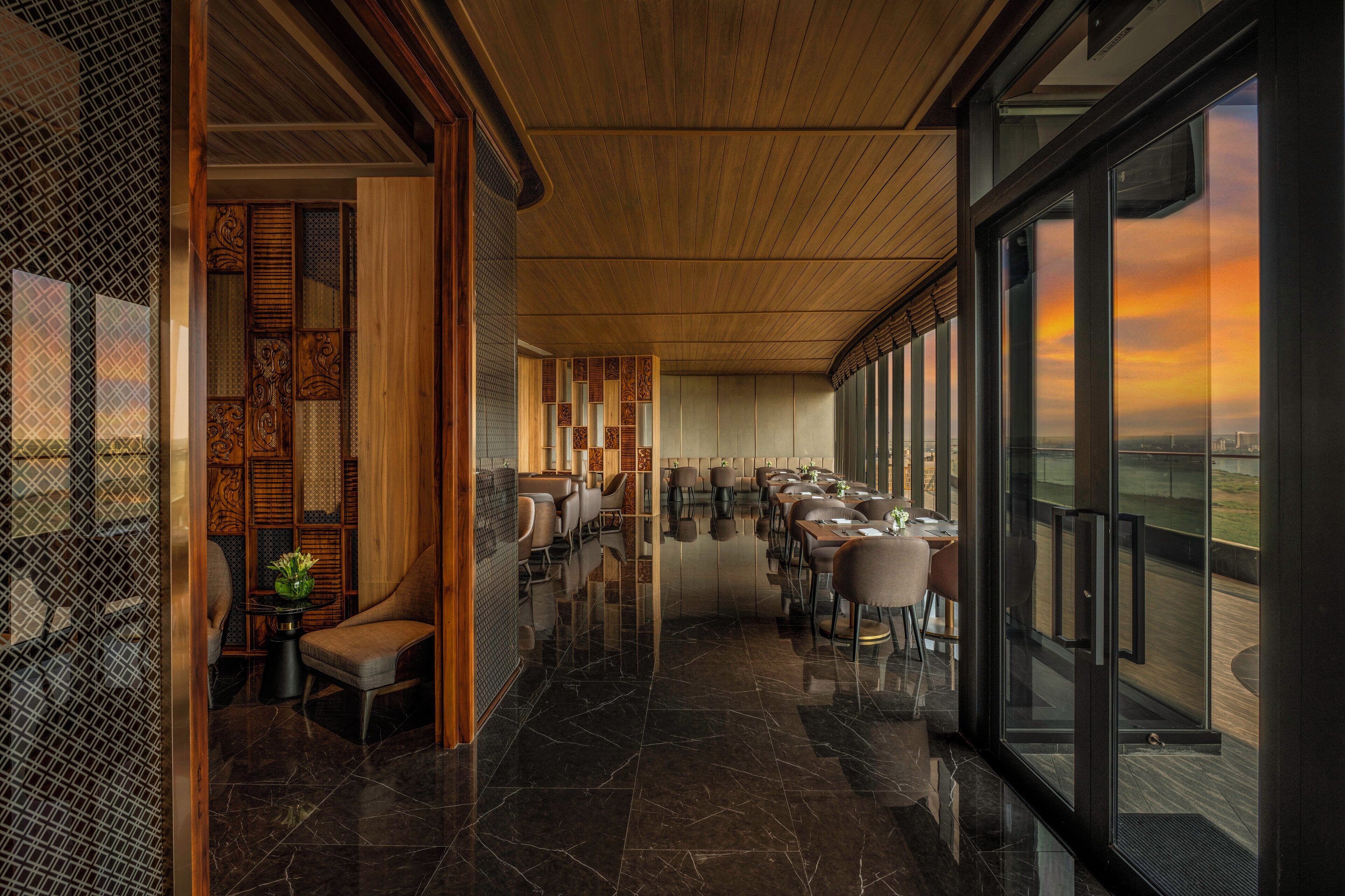 Ein modernes Restaurant mit poliertem Marmorboden, Holzboden und großen Fenstern, die einen Sonnenuntergang zeigen.