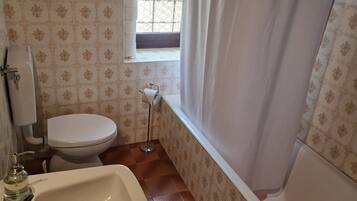 Une salle de bain avec un lavabo, des toilettes et une baignoire, le tout de couleur blanche.