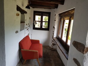 A room with a red chair, a window with a view, and exposed brick walls.