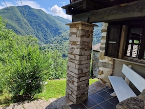 A stone pillar, a bench, and a view of a mountainous landscape.