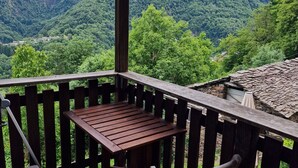 Una terraza de madera con una mesa y sillas, con vistas a un paisaje montañoso.