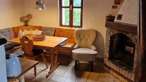 Una habitación acogedora con techo de madera, chimenea, mesa de comedor con sillas y un sofá.