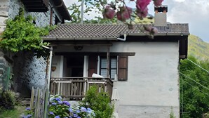 Una casa rústica con balcón, pared de piedra y valla de madera.