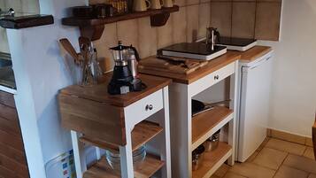 A compact kitchen with a wooden countertop, a coffee maker, and a kettle.