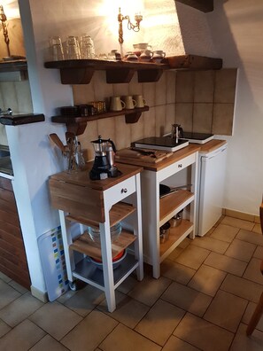 Une cuisine compacte dotée d’un plan de travail en bois, d’une machine à café et d’une bouilloire.