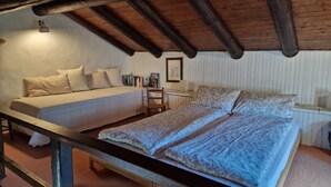 Un dormitorio con cama, una silla, una mesita de noche y techo de madera.