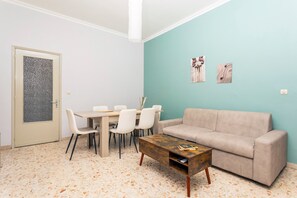 Een woonkamer met een bank, een salontafel, een eettafel met stoelen en kunstwerken aan de muur.