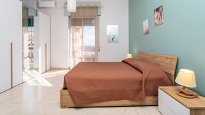 A bedroom with a bed, bedside lamp, and artwork on the wall.