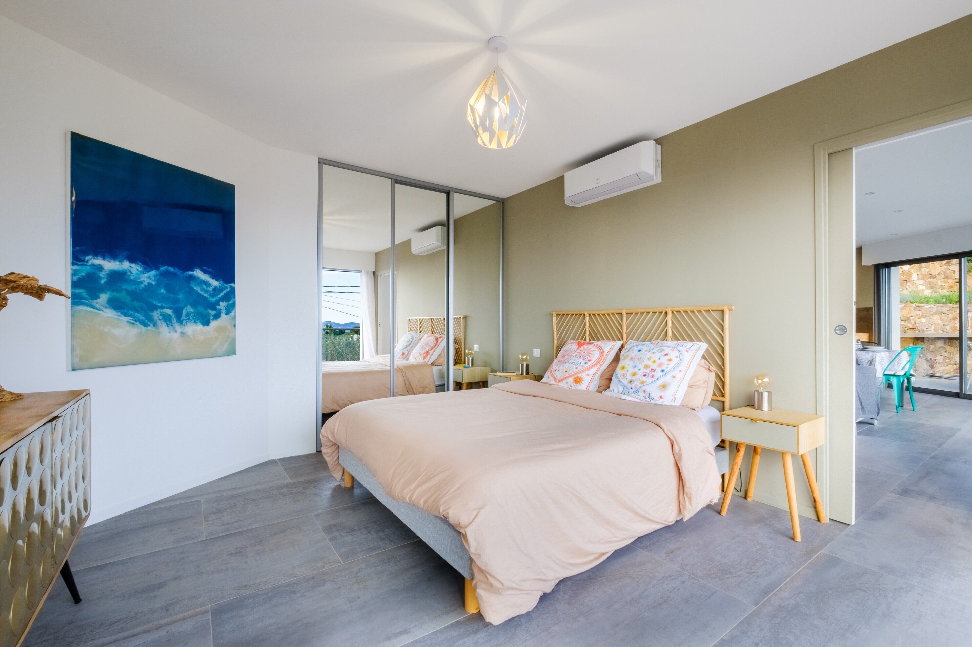 Een moderne slaapkamer met een groot bed, nachtkastje, spiegel en uitzicht op de omgeving.