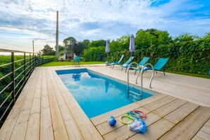 A wooden deck with a swimming pool, lounge chairs, and umbrellas. - Contemporary villa with panoramic views over Cannes Bay and private pool (Mandelieu-la-Napoule)