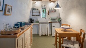 Eine kleine Küche mit Holzausstattung, einem Kühlschrank, einer Mikrowelle und einem Esstisch mit Stühlen.
