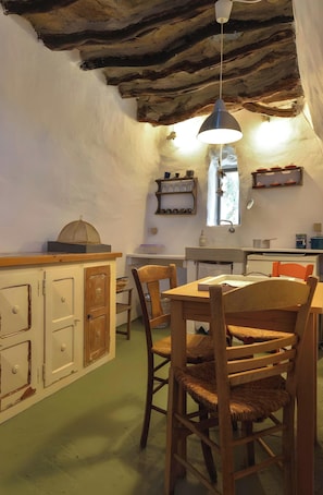 Une cuisine rustique avec des meubles de rangement en bois, une table à manger avec des chaises et un luminaire suspendu.
