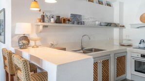 A modern kitchen with a white countertop, two pendant lights, a sink, and a built-in oven. - Apartment In A Hotel 'Anemos Suite with Private Pool' with Sea View, Wi-Fi and Air Conditioning (Laouti Tinos)
