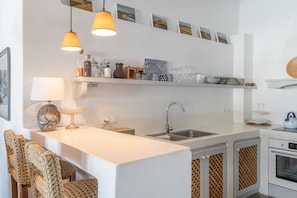 A modern kitchen with a white countertop, two pendant lights, a sink, and a built-in oven.