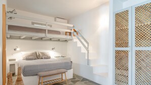 A bedroom with a bunk bed, a bedside table, a bench, and a staircase with a wooden railing. - Apartment In A Hotel 'Anemos Suite with Private Pool' with Sea View, Wi-Fi and Air Conditioning (Laouti Tinos)