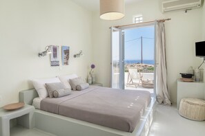 A bedroom with a bed, a bedside table, a TV, and a view of the outdoors.