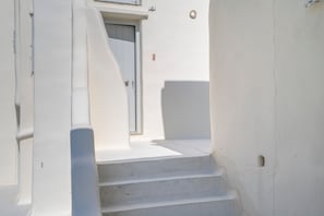 Uma escada branca que leva a uma porta com uma pequena janela acima.