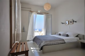 A bedroom with a bed, bedside table, and a view of the sea.