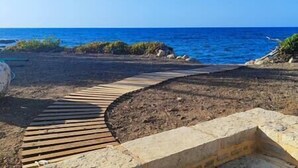 A wooden pathway leading to a beach with a clear view of the ocean. - Aqua Luna Bay Beachfront Luxury Apartment (Pigianos Kampos)