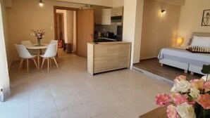 A compact living space with a kitchenette, a dining area, and a bedroom. - Aqua Luna Bay Beachfront Luxury Apartment (Pigianos Kampos)