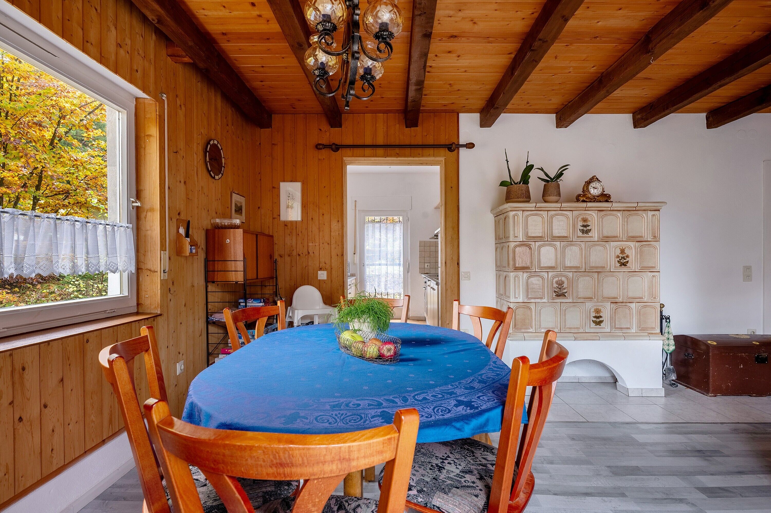 Un coin repas avec une table ronde, des chaises en bois, une nappe bleue et un lustre.