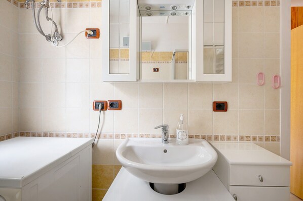 Un baño con lavamanos, espejo y ducha.