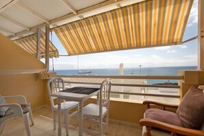 A balcony with a table and chairs, a view of the sea, and a striped awning. - Vacation 'Ceyla' with Sea View, Private Terrace and Wi-Fi (Arona)