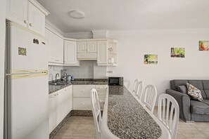 A compact kitchen with white cabinets, a granite countertop, and a dining area with white chairs. - Vacation 'Ceyla' with Sea View, Private Terrace and Wi-Fi (Arona)