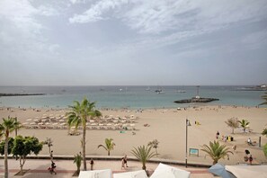 A beach with umbrellas, palm trees, and a view of the sea. - Vacation 'Ceyla' with Sea View, Private Terrace and Wi-Fi (Arona)