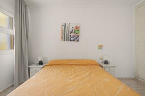 A bedroom with a bed, two bedside tables, a window with curtains, and a wall with a framed picture. - Vacation 'Ceyla' with Sea View, Private Terrace and Wi-Fi (Arona)