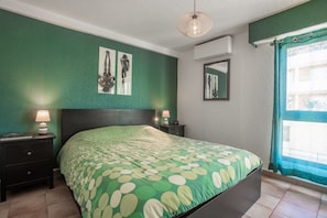 A bedroom with a bed, nightstands, a wall-mounted mirror, and artwork.