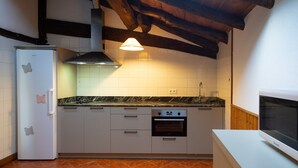 A kitchen with white cabinets, a built-in oven, a white refrigerator, and a wooden ceiling.