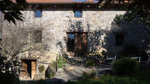 A stone building with a tiled roof, a wooden door, and a small window.