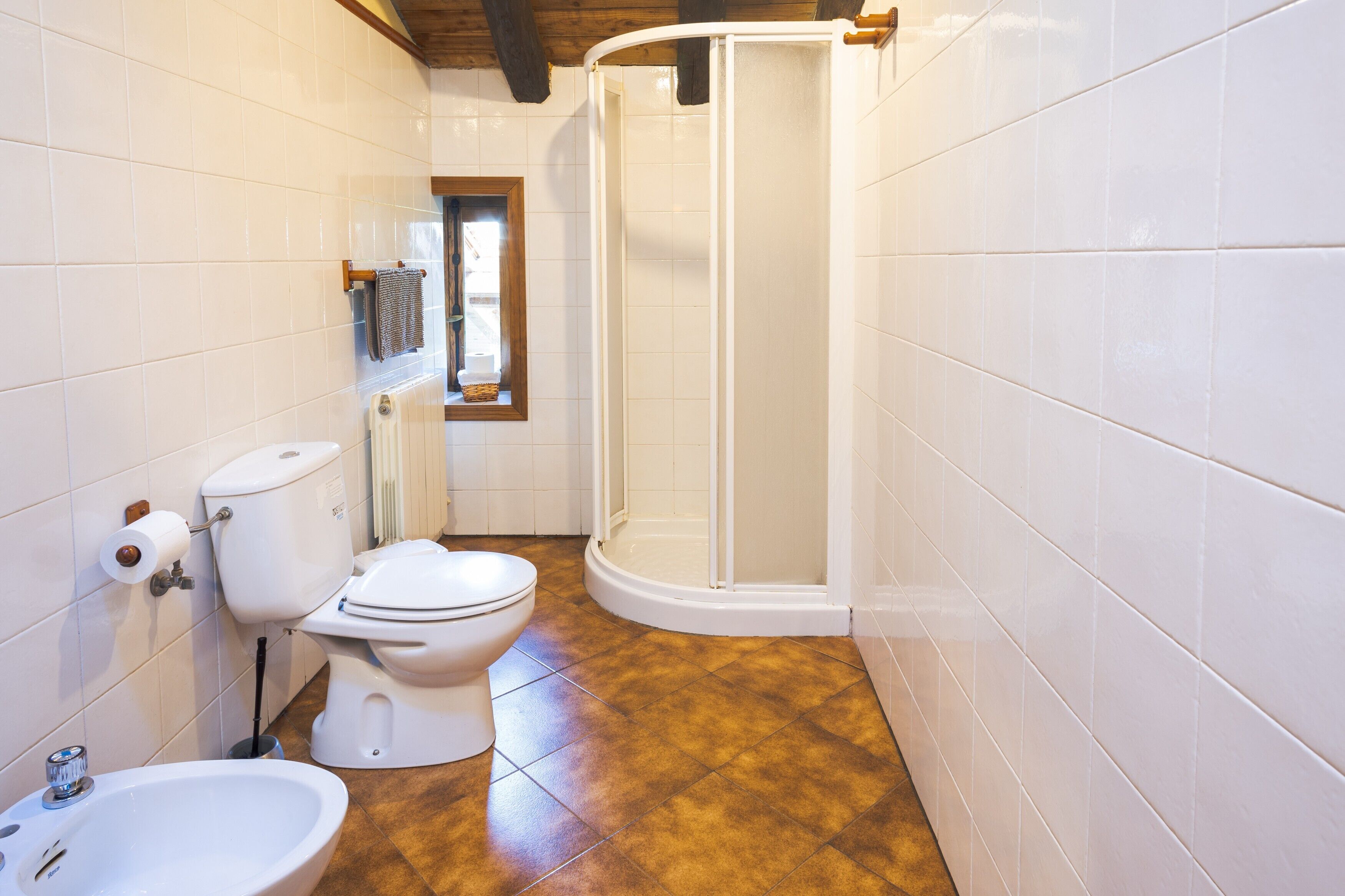 Ein Badezimmer mit Toilette, Bidet, Waschbecken und Duschbereich.